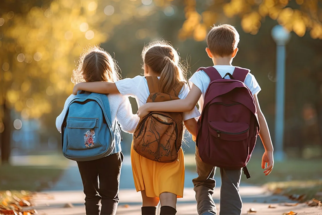 trois enfants avec sac-a-dos se tenant par les épaules